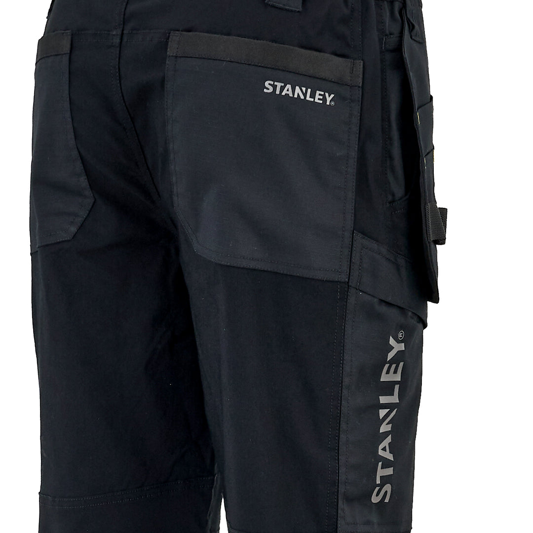 Close-up of black work pants showing the back pocket with the white STANLEY logo and the vertical STANLEY branding on the leg.