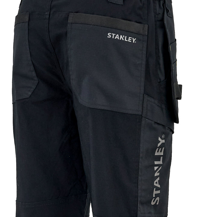 Close-up of black work pants showing the back pocket with the white STANLEY logo and the vertical STANLEY branding on the leg.