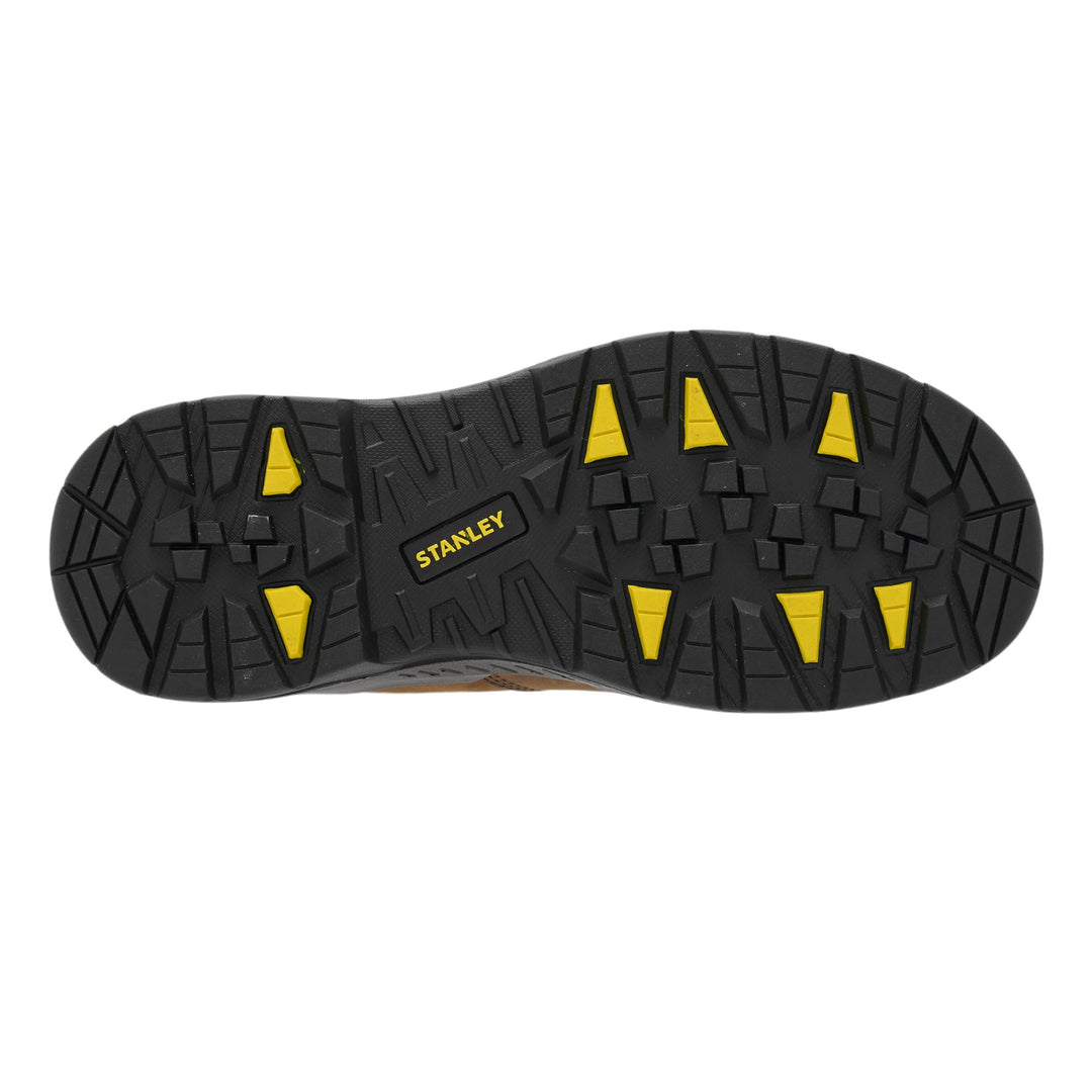 The treaded black rubber outsole of a Stanley work boot, featuring bright yellow triangular lugs and a yellow Stanley logo, shown against a plain white background.